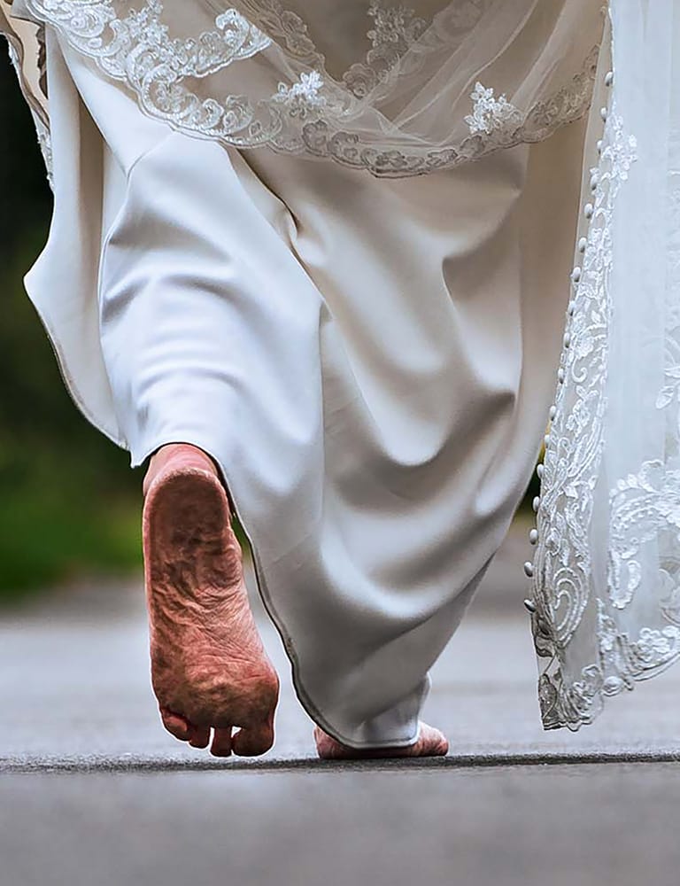 Blote voeten van de bruid en bewegende kanten jurk, dynamisch moment – spontane trouwfoto in Limburg