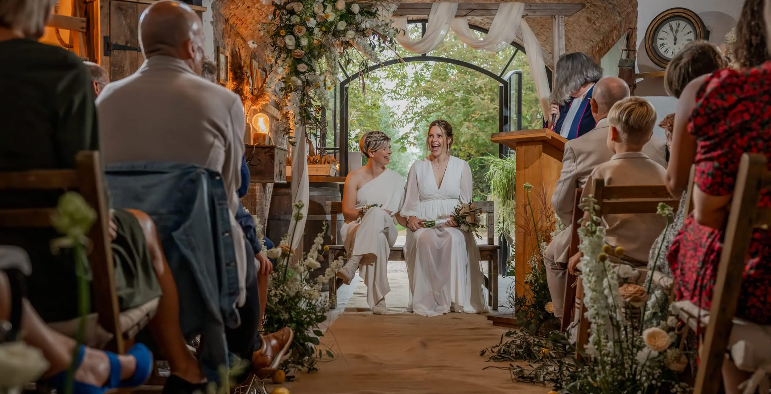 Twee bruiden lachen tijdens de ceremonie in de molen – bruidsfotografie in Limburg